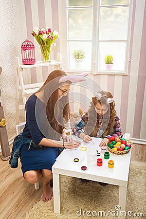 Easter - Mother and daughter paint eggs, bunny ears Stock Photo