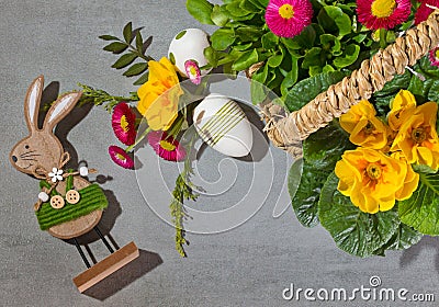 Easter rebbit and Easter eggs with spring flowers in a wicker basket. Stock Photo