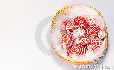 Easter red eggs with folk white pattern lay on feather into basket on white background, top view. Ukrainian traditional eggs Stock Photo