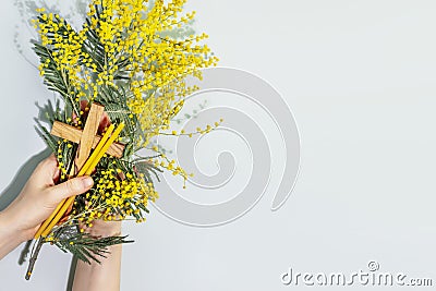 Womans hands hold wooden crucifixion, mimosa sprig and copy space Stock Photo