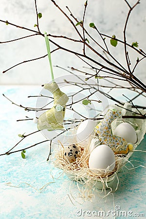 Easter scene with spring fresh greenery branches, rabbit and nest of eggs, springtime festive background. Stock Photo