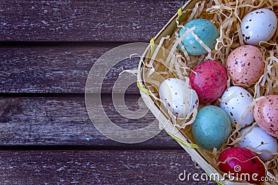 Multicolored easter eggs in a basket on a brown wooden table, Ea Stock Photo