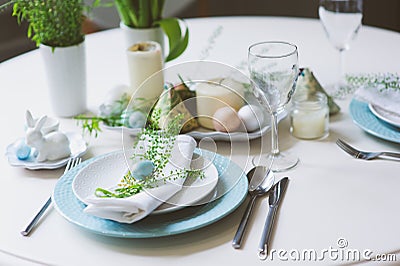 Easter and spring festive table decorated in blue and white tones in natural rustic style, with eggs, bunny, fresh flowers Stock Photo