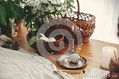 Easter Stylish Rural still life. Stylish Easter egg with modern wax ornaments and natural dyed eggs on rustic wooden table with Stock Photo