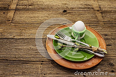 Easter table setting on antique wooden background. Spring holiday card template. Cutlery, crochet napkin, egg, twigs of lilac Stock Photo