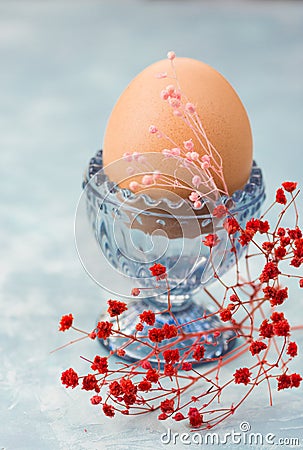 Easter table setting, decoration,egg in blue crystal cup with tender spring red and pink flowers Stock Photo