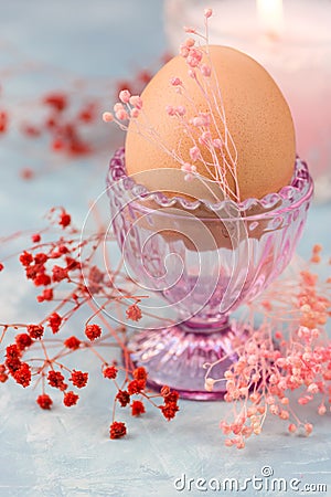 Easter table setting, decoration,egg in crystal cup with tender spring red and pink flowers, burning candle Stock Photo