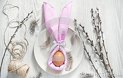 Easter table setting. A napkin in the form of an Easter bunny on a plate. Light background. Copy space Stock Photo