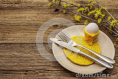 Easter table setting on old wooden background. Spring holiday card template. Cutlery, crochet napkin, egg, flowering sprigs of Stock Photo