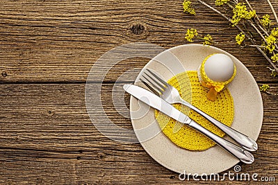 Easter table setting on old wooden background. Spring holiday card template. Cutlery, crochet napkin, egg, flowering sprigs of Stock Photo