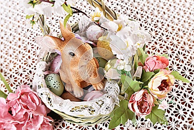 Easter wicker basket with floral decoration and cute bunny figurine Stock Photo