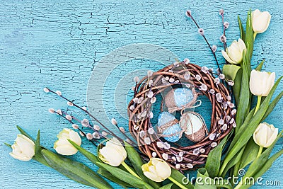 Easter willow wreath, white tulips and blue Easter eggs on blue background Stock Photo