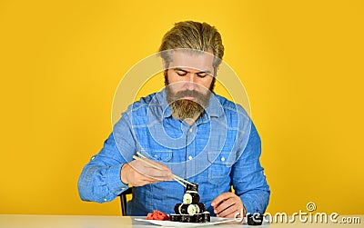 Eastern culture. Bearded hipster eating rolls. Japanese food delivery. Sushi rolls. Japanese cuisine. Asian meal. Sushi Stock Photo