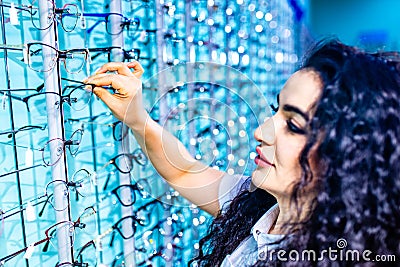 eastern ethnic woman in white medical coat robe selling glasses in optical store Stock Photo