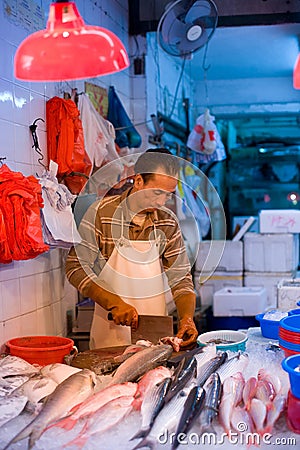 A fishmonger at a fresh fish shop on the markets of Chun Yeung Street in North Point district at Hong Kong Editorial Stock Photo