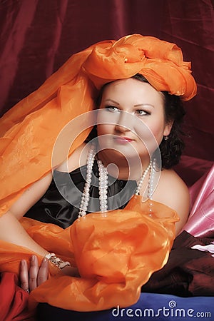 Woman in oriental robes is lazily laying on pillows Stock Photo