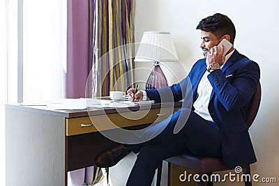 Eastern man in suit working in hotel, talking by phone Stock Photo