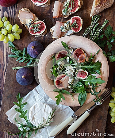 Easy diet salad with arugula, figs and blue cheese on a brown wooden surface. Sandwiches with ricotta, fresh Stock Photo
