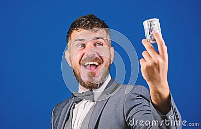 Easy money concept. Rich businessman hold rolled money. Man bearded hipster hold rolled dollars banknotes. Guy formal Stock Photo