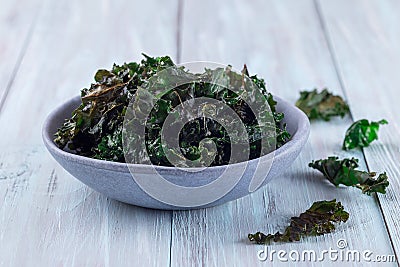 Easy three ingredient baked green kale chips with sea salt and olive oil, in gray bowl, horizontal Stock Photo