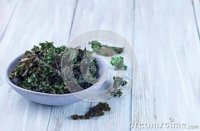 Easy three ingredient baked green kale chips with sea salt and olive oil, in gray bowl, horizontal, copy space Stock Photo