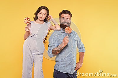 Eat dessert first. Happy family hold candy dessert on stick. Father and daughter yellow background. Bearded man and Stock Photo