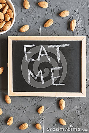 `Eat me` phrase written on a small blackboard and raw almond Stock Photo