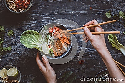 Eating delicious asian bowl with rice noodles, vegetables and to Stock Photo