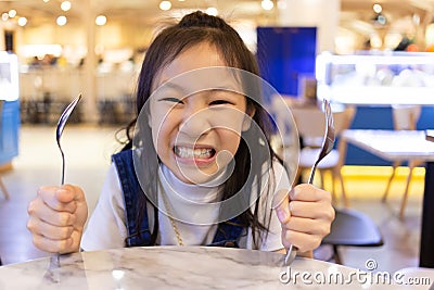 Eating disorder,Asian cute girl hungry waiting for lunch and order in the restaurant,Holding for a spoon and fork,hangry Stock Photo