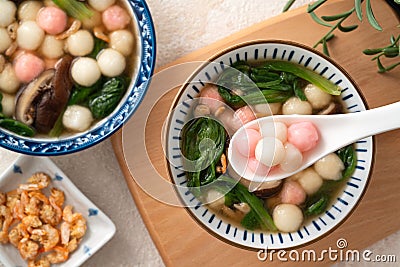 Eating homemade red and white small tangyuan with savory soup and vegetable Stock Photo