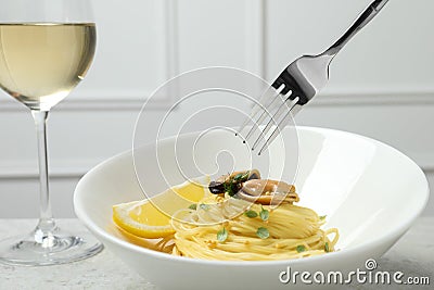 Eating tasty capellini with mussels and lemon at light grey table, closeup. Exquisite presentation of pasta dish Stock Photo