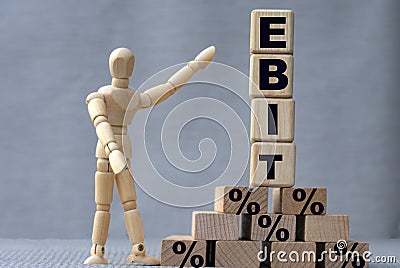 EBIT , the word is on cubes on a gray background, next to it is a wooden man Stock Photo