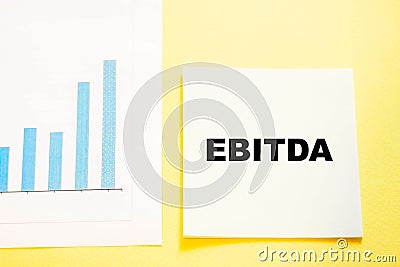 EBITDA business expression on office paper with yellow background Stock Photo