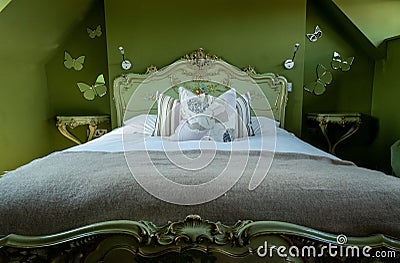 Eclectic bedroom with French Rococo style bed, and walls painted in deep green colour. Stock Photo