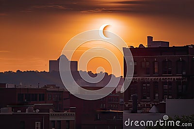 the eclipse, with the moon in front of the sun, and a view of silhouette buildings in the background Stock Photo