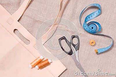 eco bag, scissors, measuring tape and several spools of thread on linen fabric Stock Photo