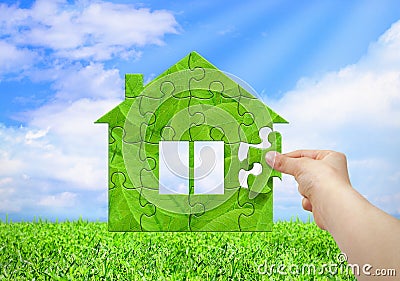 Eco home concept, hand build green house from puzzle. Stock Photo