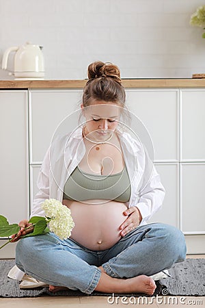 Eco pregnancy. Pregnant woman with big belly advanced pregnancy holding white flower hydrangea in hand at home. Healthy Stock Photo