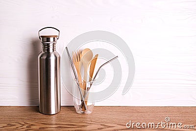 Eco set with bamboo cutlery, reusable water bottle on wooden background. Stock Photo