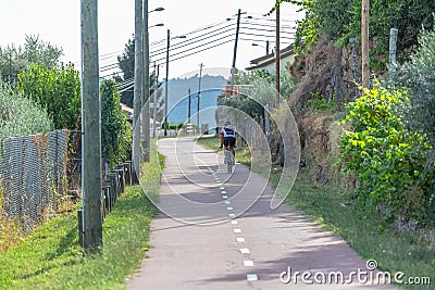 Eco view pedestrian / cycle lane, with cyclist pedaling and agricultural fields around Editorial Stock Photo