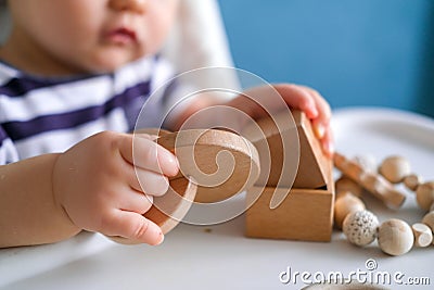 Eco wood toys. baby game. Little clever caucasian child playing natural toys on highchair. games for early development Stock Photo
