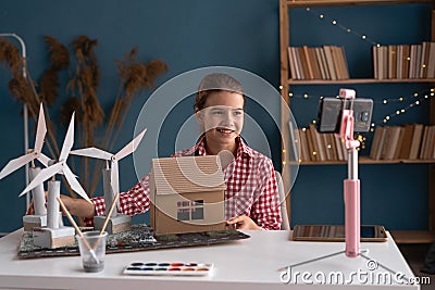 Ecology, technology and energy saving concept. Teen blogger recording video about wind turbines project from her home Stock Photo