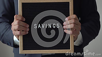 Economias da palavra das letras na placa do texto no homem de negócios anônimo Hands Economias da palavra das letras na placa do texto no homem de negócios anônimo Hands