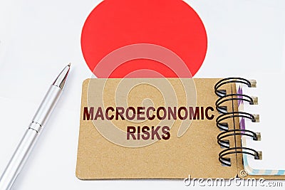 On the flag of Japan lies a pen and a notebook with the inscription - macroeconomic risks Stock Photo