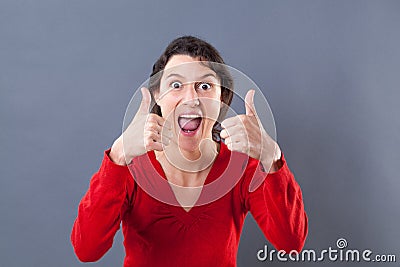 Ecstatic young woman shouting with thumbs up for excitement Stock Photo
