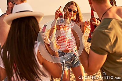 Ecstatic youth drinking alcohol and dancing on beach Stock Photo