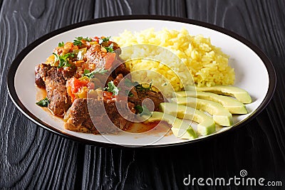 Ecuadorian traditional food: seco de chivo goat meat with a garnish of yellow rice and avocado close-up. horizontal Stock Photo