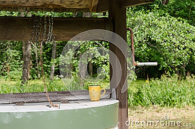 Edge of old well pulley with chain and mottled cup Stock Photo