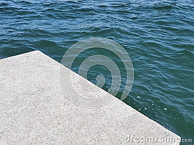 Edge of stone pier next to rippled green ocean Stock Photo