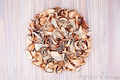 Edible dried mushrooms pile light wooden background closeup top view, dry boletus edulis heap wood backdrop, brown cap boletus Stock Photo